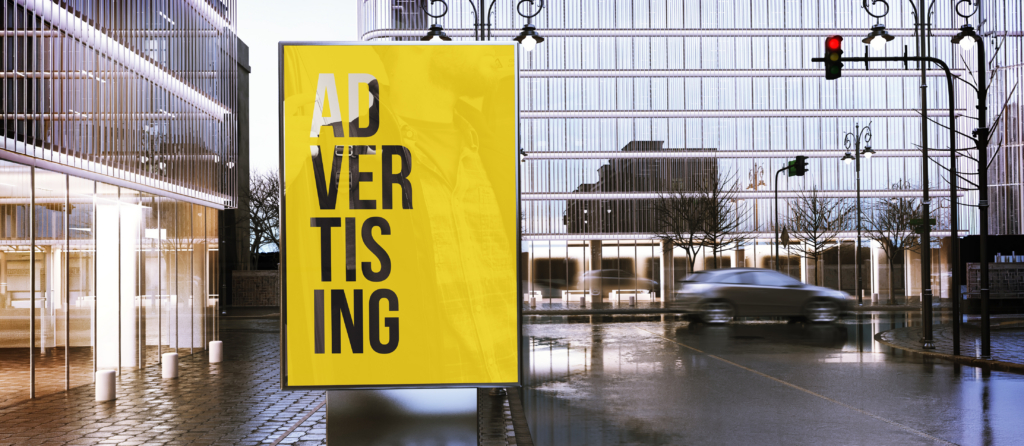 An OOH advertising kiosk on the sidewalk near a city street with a car passing in the background.